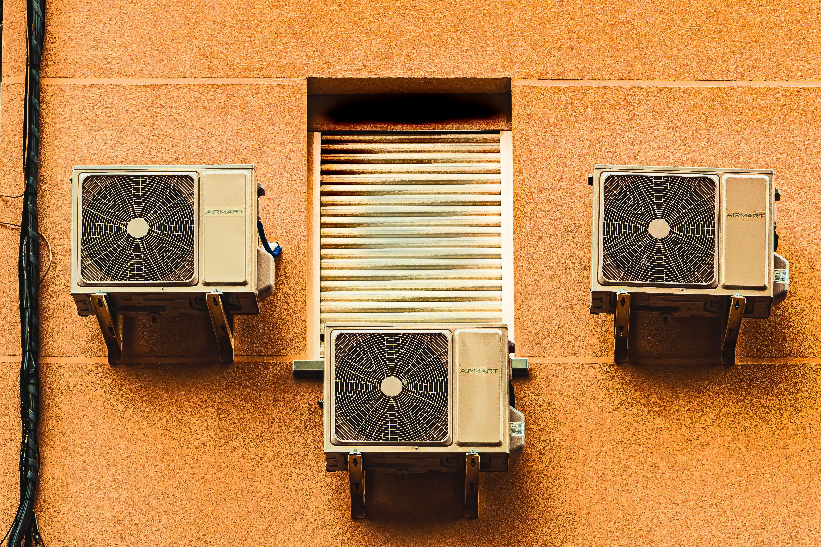 three air conditioning units on an orange wall